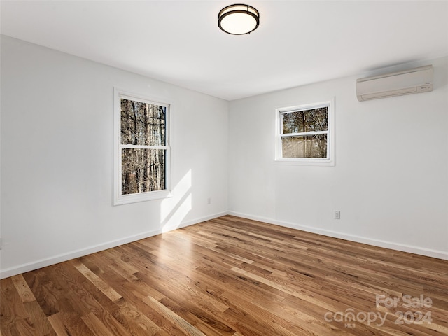 spare room featuring wood-type flooring and an AC wall unit