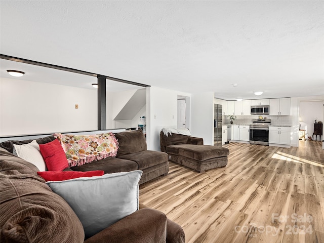 living room featuring light wood-type flooring and a textured ceiling