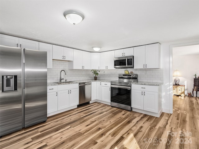 kitchen featuring appliances with stainless steel finishes, white cabinets, tasteful backsplash, and sink