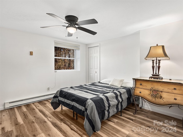 bedroom with a baseboard heating unit, ceiling fan, a closet, and hardwood / wood-style floors