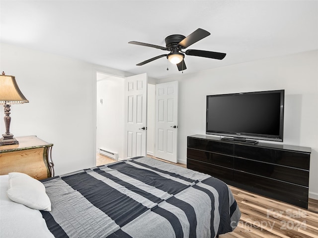 bedroom with a baseboard heating unit, ceiling fan, and wood-type flooring