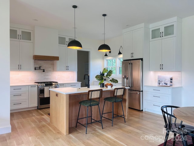 kitchen with tasteful backsplash, a center island with sink, light hardwood / wood-style flooring, and appliances with stainless steel finishes