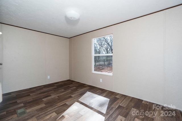 spare room featuring a textured ceiling, dark hardwood / wood-style floors, and crown molding