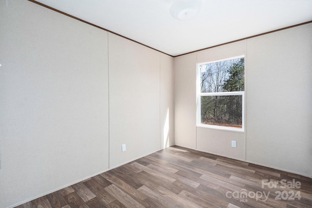 spare room with ornamental molding and dark wood-type flooring