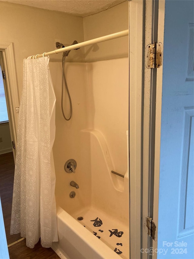 bathroom featuring a textured ceiling, shower / tub combo with curtain, and hardwood / wood-style floors