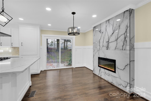 unfurnished living room featuring a high end fireplace, dark wood-type flooring, and ornamental molding