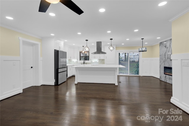 kitchen featuring a center island, wall chimney range hood, dark hardwood / wood-style floors, and white cabinets