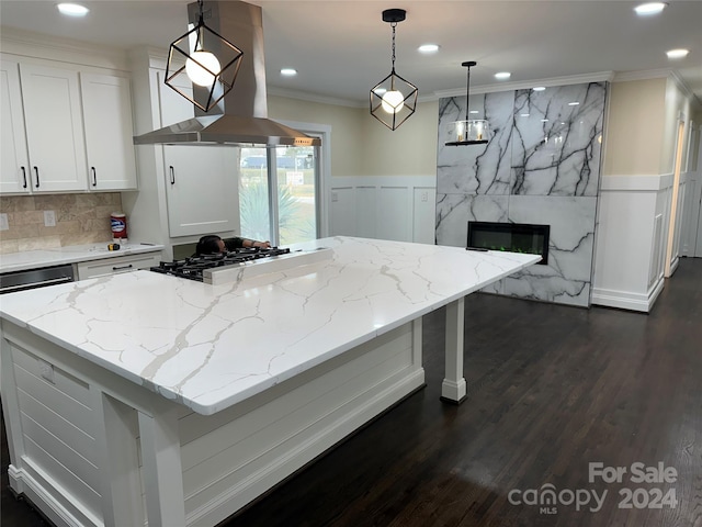 kitchen featuring range hood, decorative light fixtures, dark wood-type flooring, a premium fireplace, and white cabinetry