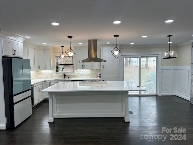 kitchen featuring a kitchen island, white cabinetry, dark hardwood / wood-style flooring, and wall chimney range hood