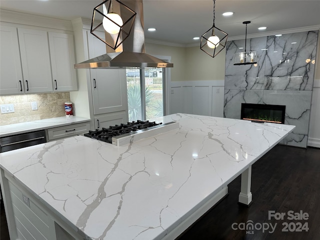 kitchen with light stone countertops, range hood, decorative light fixtures, and dark hardwood / wood-style floors