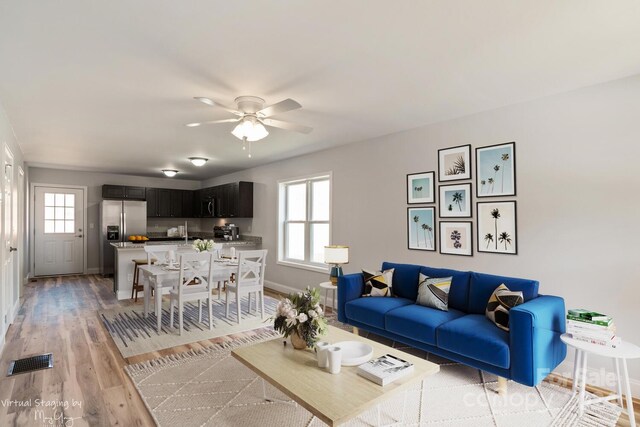 living room featuring ceiling fan, a healthy amount of sunlight, and light wood-type flooring