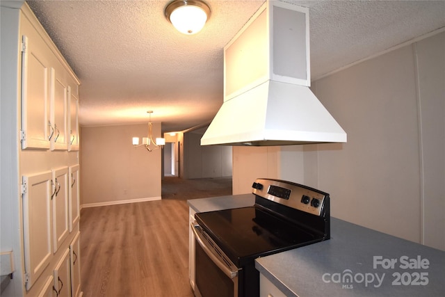 kitchen with white cabinetry, island exhaust hood, hanging light fixtures, a notable chandelier, and electric range