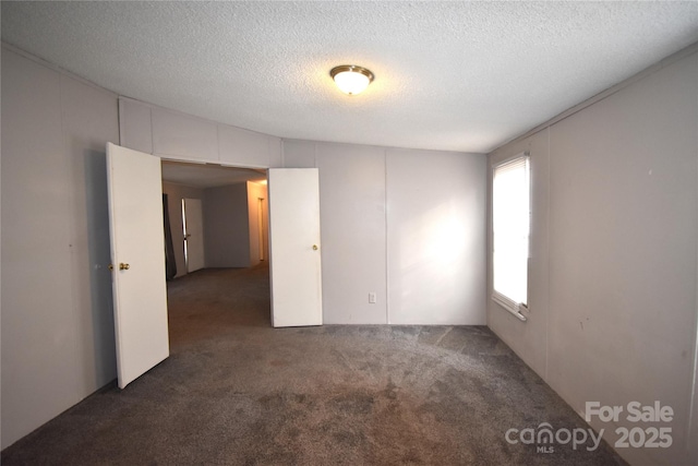 carpeted spare room featuring a textured ceiling