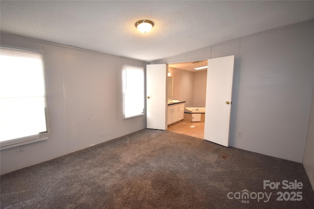 unfurnished bedroom featuring light carpet, connected bathroom, and a textured ceiling