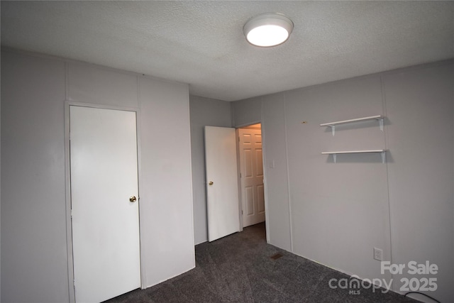 unfurnished bedroom featuring a closet, a textured ceiling, and dark colored carpet