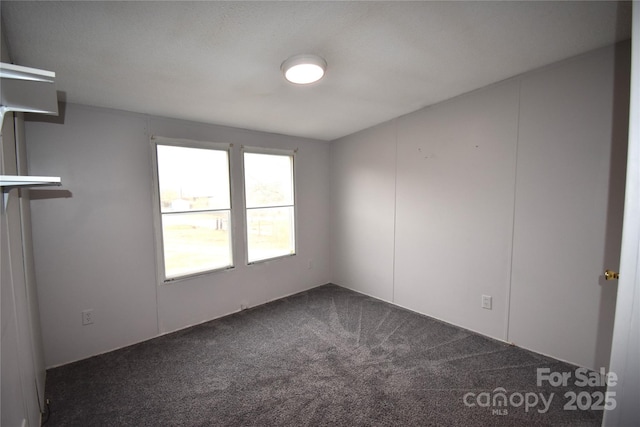 spare room featuring dark colored carpet