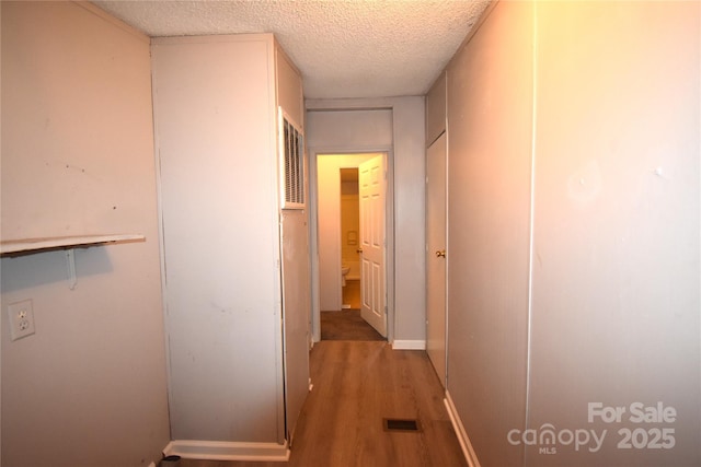 hallway featuring wood-type flooring and a textured ceiling