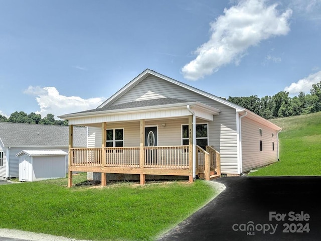 view of front of house with a shed, covered porch, and a front lawn