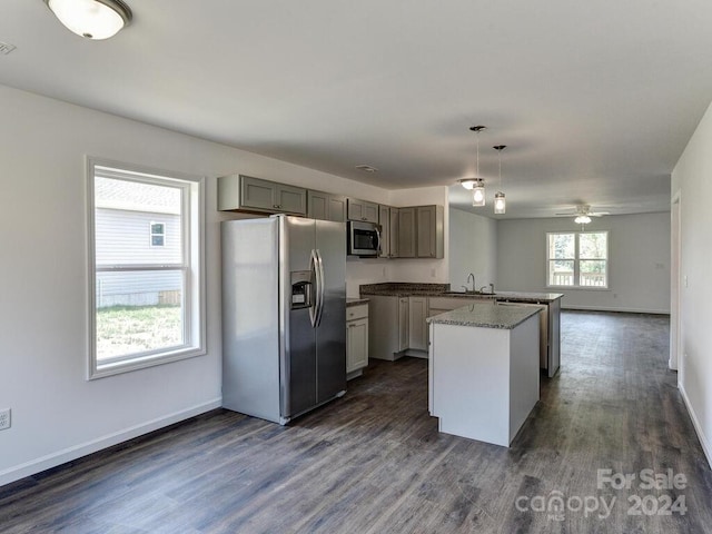 kitchen featuring ceiling fan, a kitchen island, stainless steel appliances, dark wood-type flooring, and decorative light fixtures