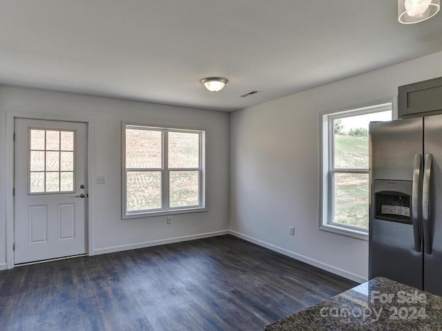 interior space featuring dark stone countertops, dark hardwood / wood-style floors, and stainless steel fridge