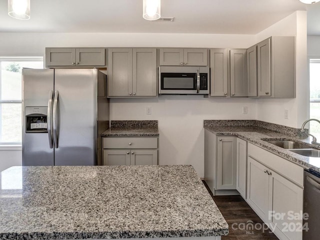 kitchen with dark stone countertops, dark wood-type flooring, and appliances with stainless steel finishes