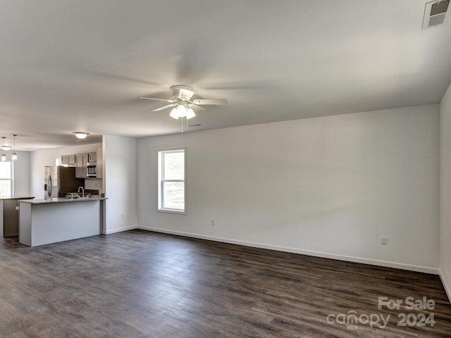 unfurnished living room featuring dark wood-type flooring, ceiling fan, and sink