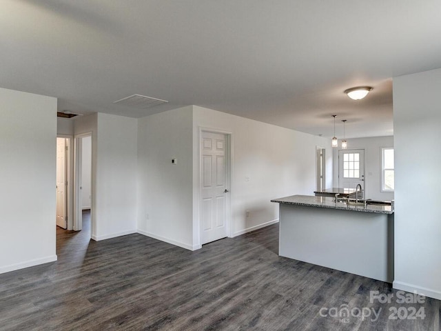 kitchen with dark hardwood / wood-style flooring, sink, pendant lighting, and stone countertops