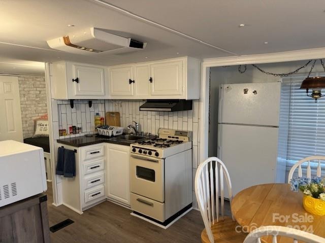 kitchen with dark wood-type flooring, white appliances, sink, white cabinets, and tasteful backsplash