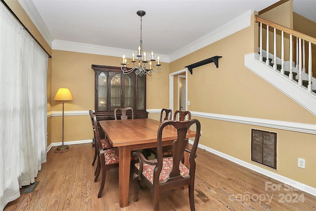 dining space with hardwood / wood-style floors, crown molding, and a chandelier