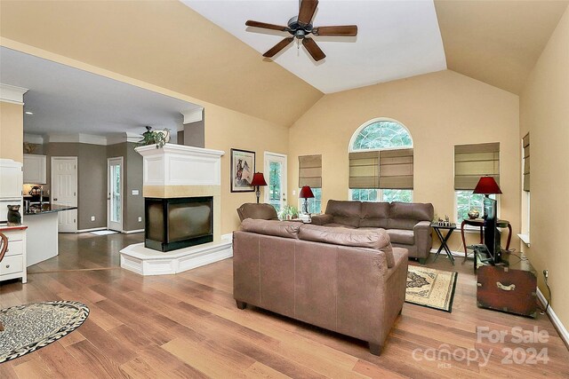 living room with lofted ceiling, light hardwood / wood-style floors, ceiling fan, and a multi sided fireplace