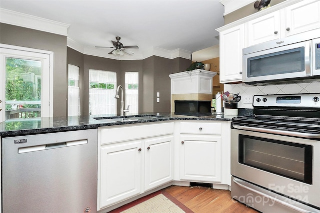 kitchen featuring sink, stainless steel appliances, dark stone counters, and white cabinets