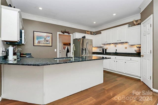 kitchen with appliances with stainless steel finishes, white cabinetry, sink, kitchen peninsula, and crown molding