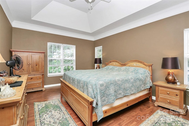 bedroom featuring dark hardwood / wood-style flooring, a tray ceiling, crown molding, and ceiling fan