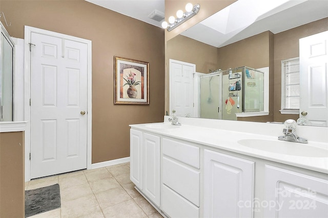 bathroom with vanity, a skylight, tile patterned floors, and a shower with shower door