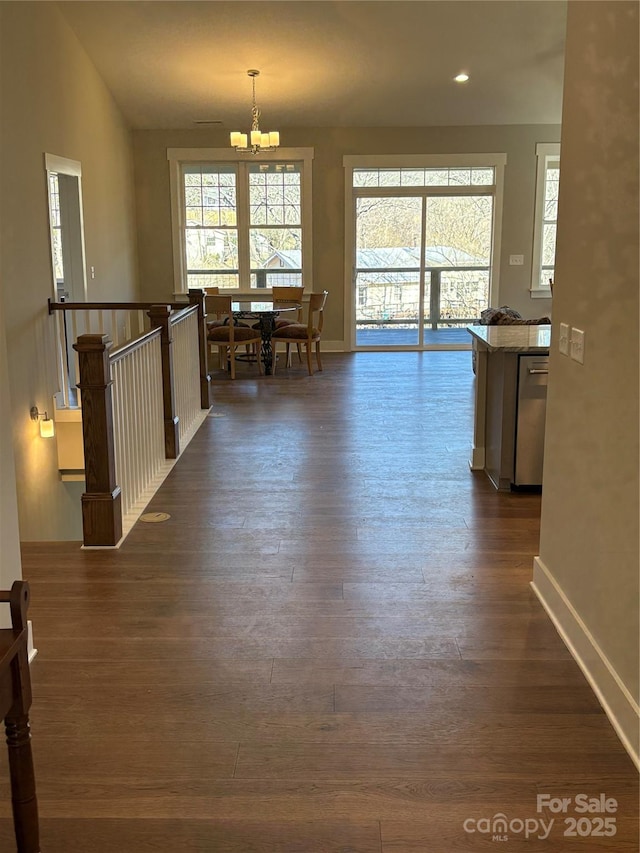 hallway with a notable chandelier, lofted ceiling, and dark hardwood / wood-style floors