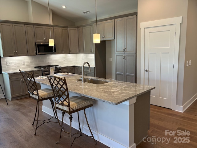 kitchen featuring stainless steel appliances, sink, light stone counters, decorative backsplash, and hanging light fixtures