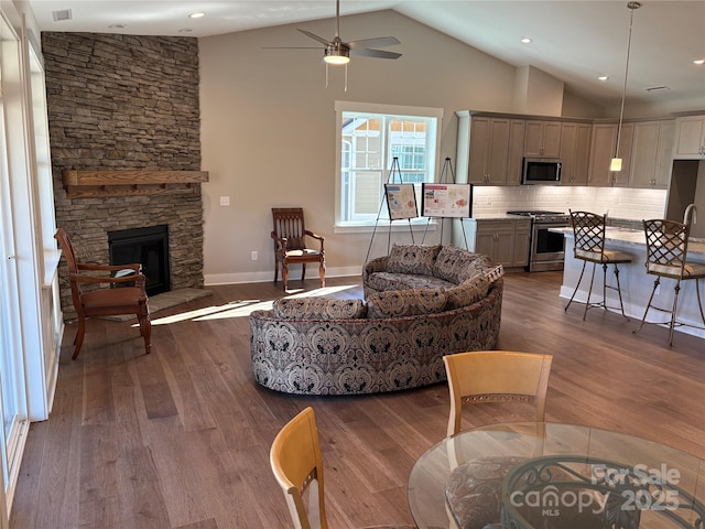 living room featuring wood-type flooring, a fireplace, ceiling fan, and vaulted ceiling