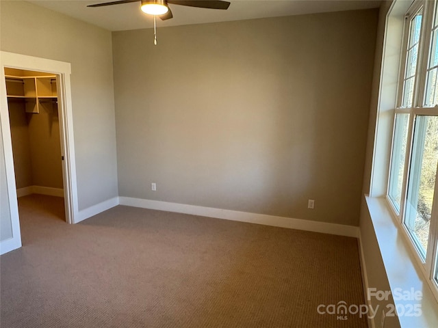 unfurnished bedroom with a walk in closet, ceiling fan, a closet, and carpet flooring