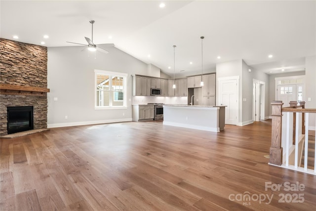 unfurnished living room featuring a sink, ceiling fan, light wood finished floors, and a healthy amount of sunlight
