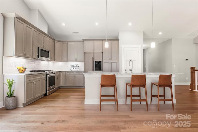 kitchen with tasteful backsplash, high quality appliances, gray cabinetry, and a breakfast bar