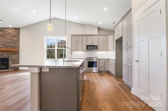 kitchen featuring light wood-style floors, gray cabinets, a sink, lofted ceiling, and stainless steel appliances