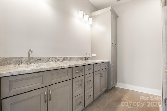 full bathroom with double vanity, baseboards, and a sink