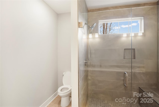 bathroom featuring toilet, baseboards, and a stall shower