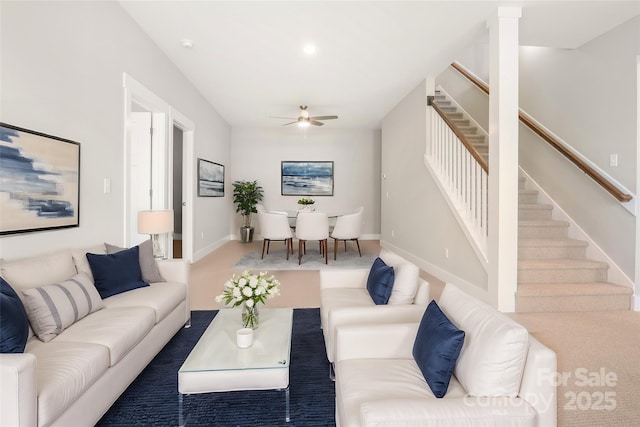 living area with ceiling fan, stairway, carpet, and baseboards