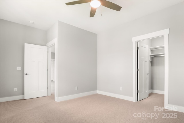 unfurnished bedroom with a walk in closet, light colored carpet, and baseboards