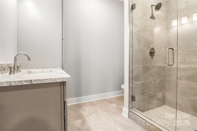 bathroom featuring a stall shower, vanity, baseboards, and tile patterned floors
