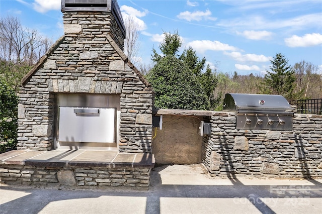exterior space featuring area for grilling, a grill, and an outdoor stone fireplace