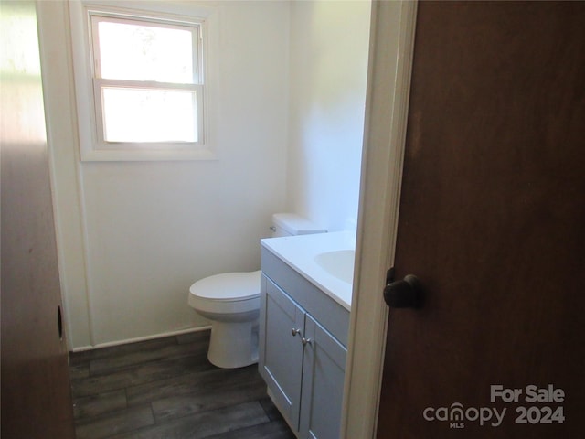 bathroom with toilet, vanity, and hardwood / wood-style floors