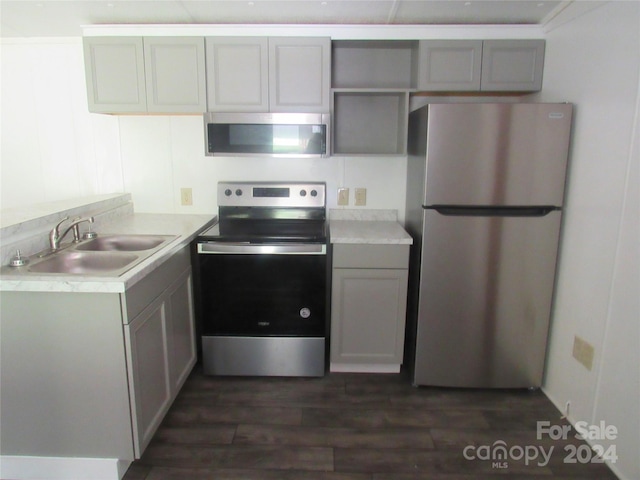 kitchen featuring dark wood-type flooring, appliances with stainless steel finishes, gray cabinetry, and sink