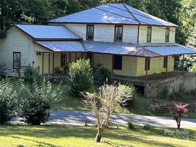 country-style home featuring covered porch and a front yard